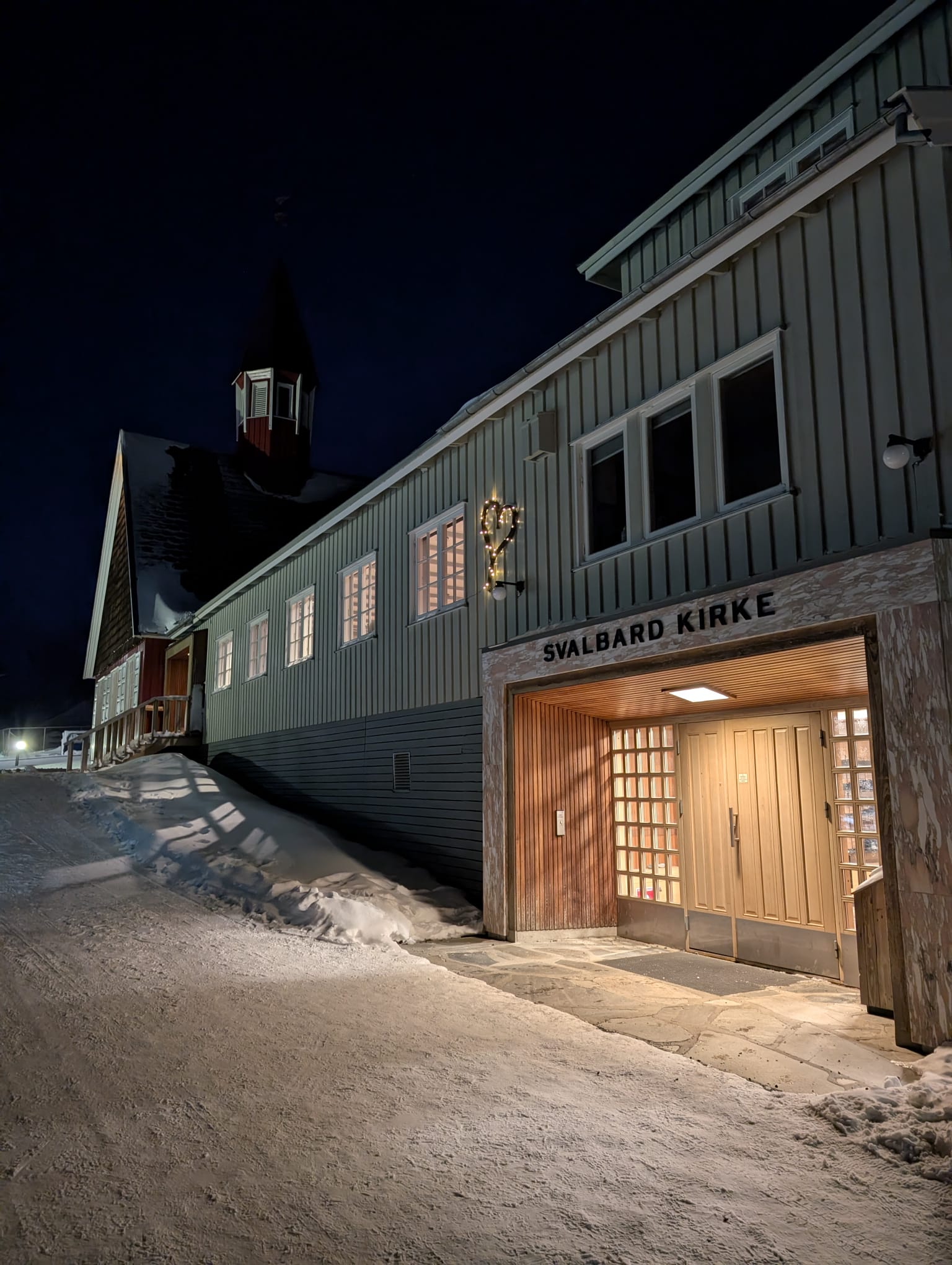 Illuminated entrance of Svalbard Church in the snow at night