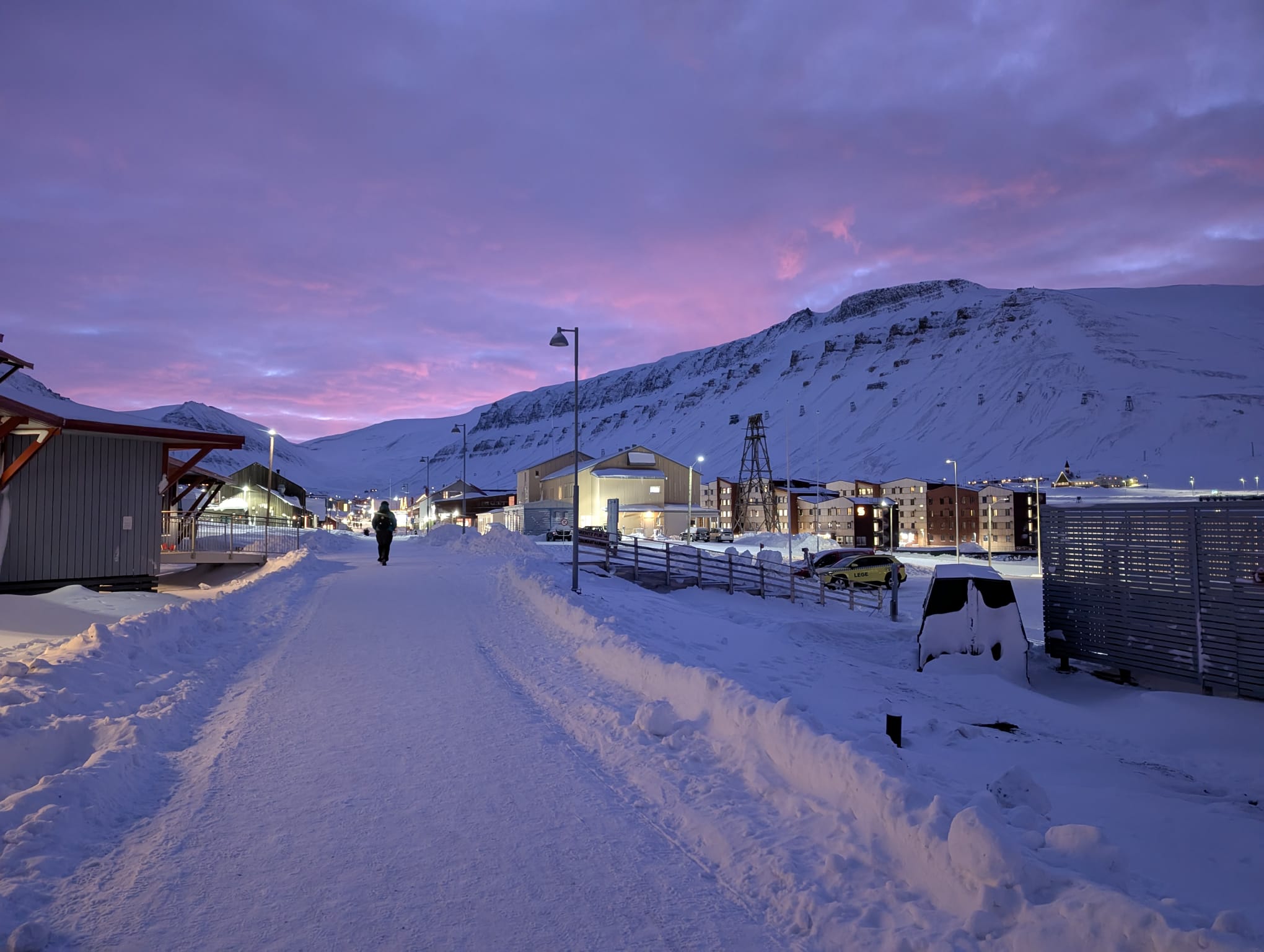 Snowy Longyearbyen street beneath a pink and blue winter sky