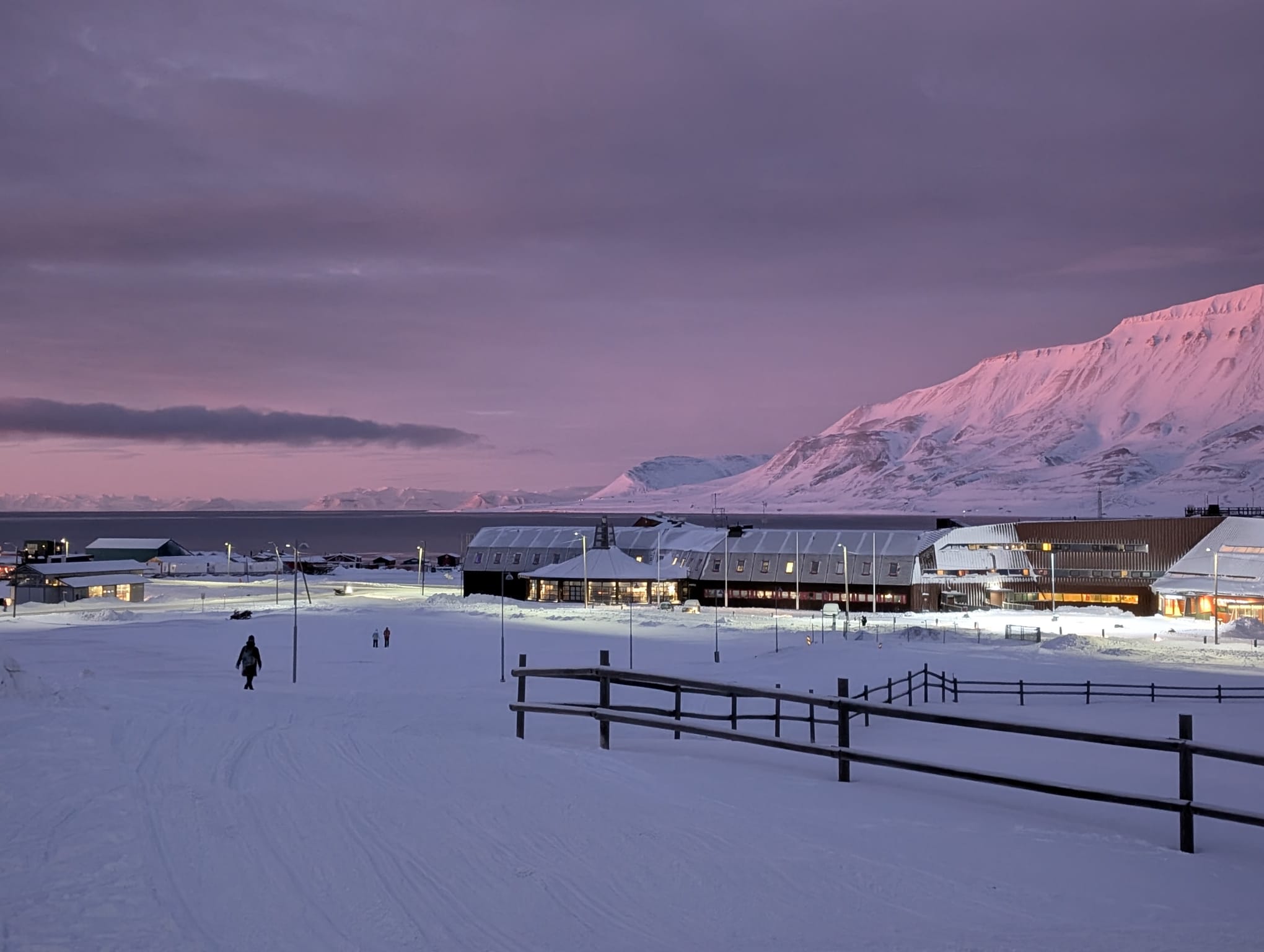 Pastel pink sky above the Longyearbyen waterfront and snowy mountains during the dark season