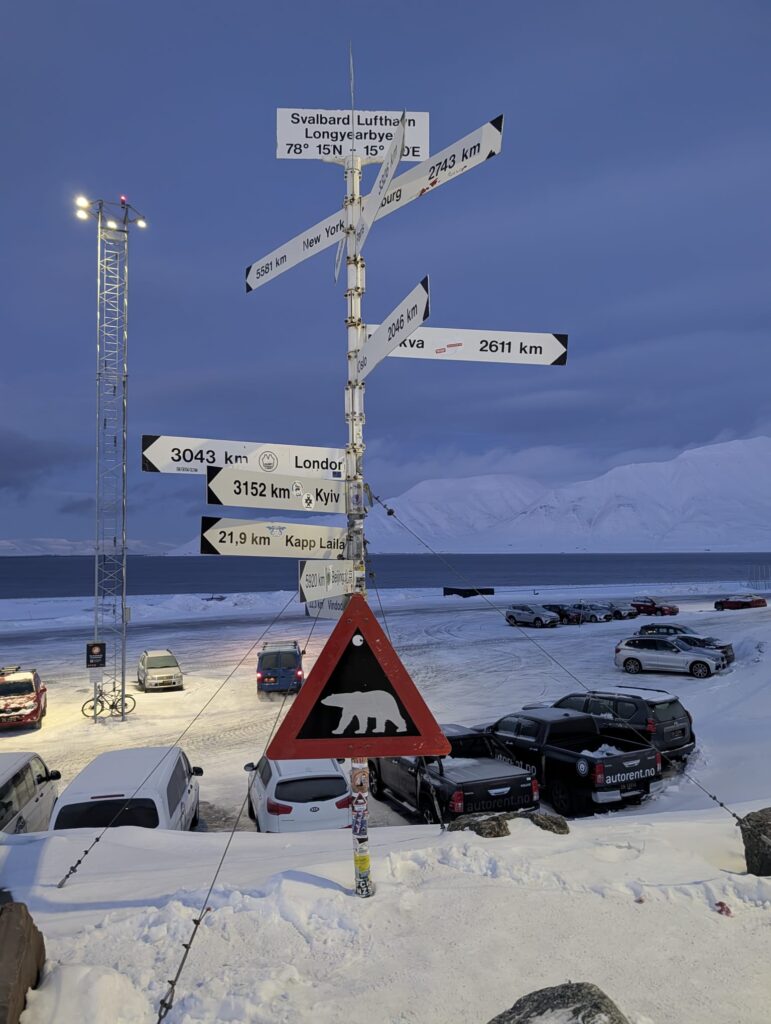 Longyearbyen Svalbard signpost and polar bear warning sign during Polar Night