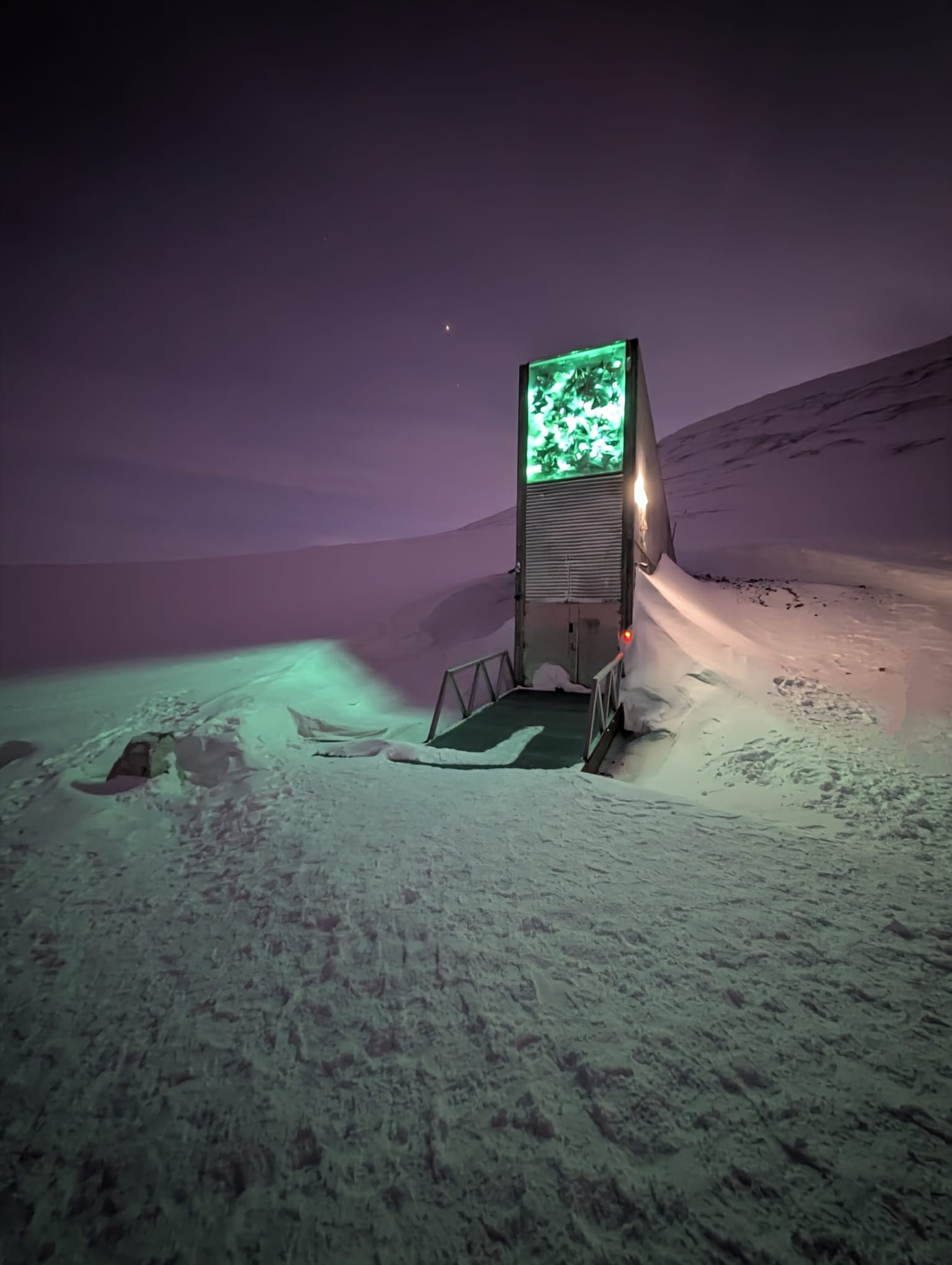 Illuminated exterior entrance of the Svalbard Global Seed Vault surrounded by snow